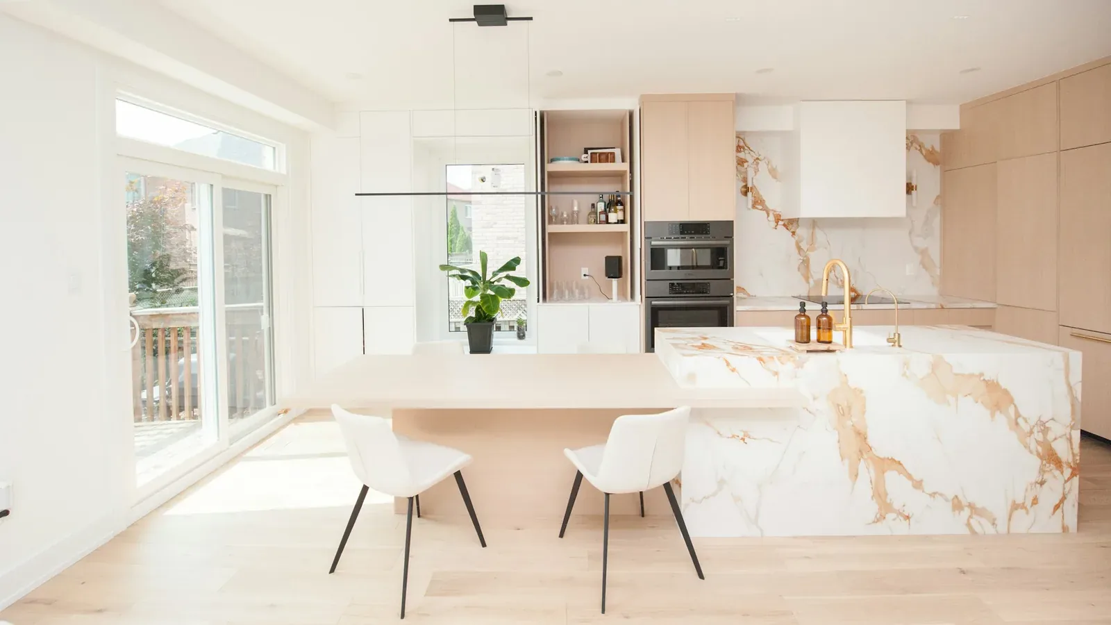 Bright contemporary kitchen with a dramatic stone waterfall island and full-height backsplash